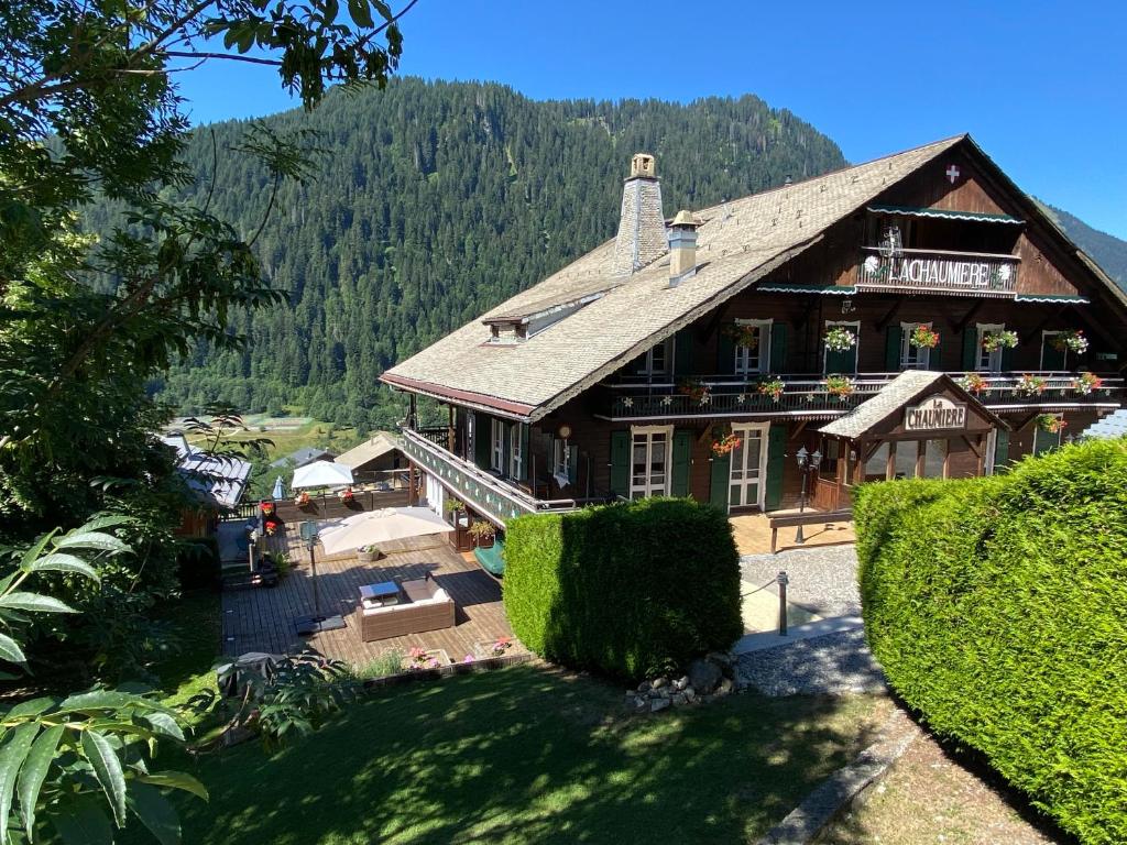 a large wooden building with a mountain in the background at La Chaumiere - Luxury Traditional Chalet, Châtel in Châtel
