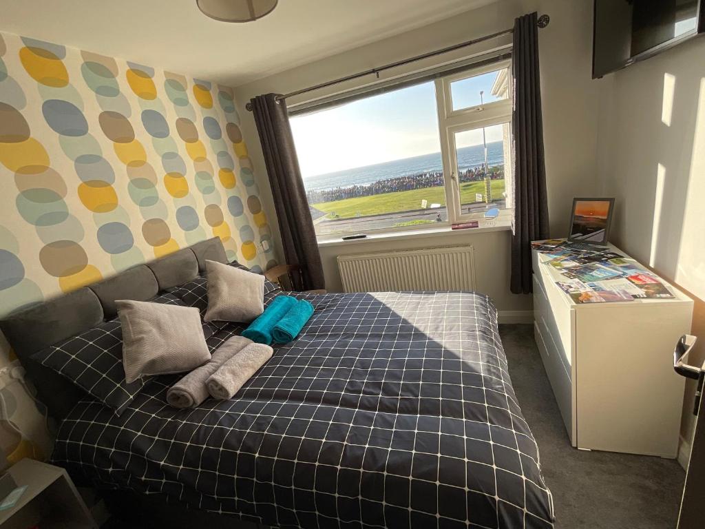 1 dormitorio con 1 cama con manta a cuadros y ventana en NUMBER 5 Portrush Road, Portstewart, en Portstewart