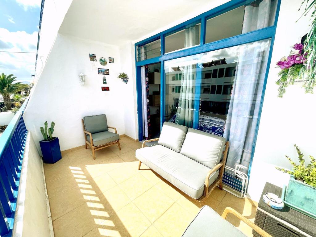 a balcony with a white couch and a chair at Casita Mara! 2’ Line to the sea, shops and bar’s in Puerto del Carmen