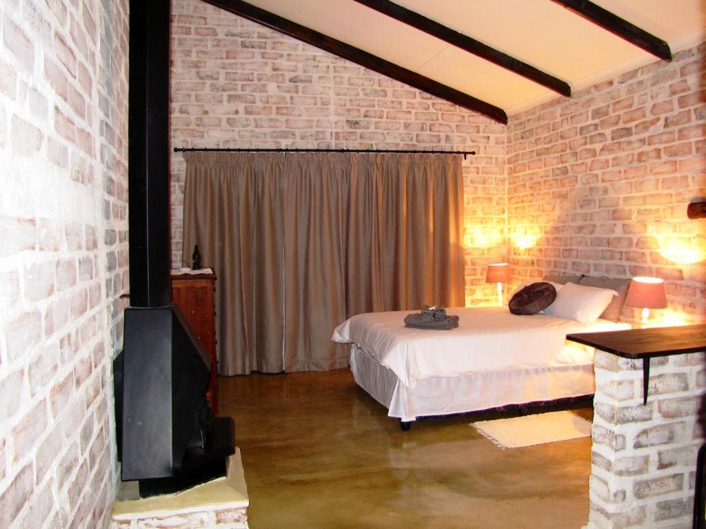 1 dormitorio con cama y pared de ladrillo en Stonefly Cottages, en Dullstroom