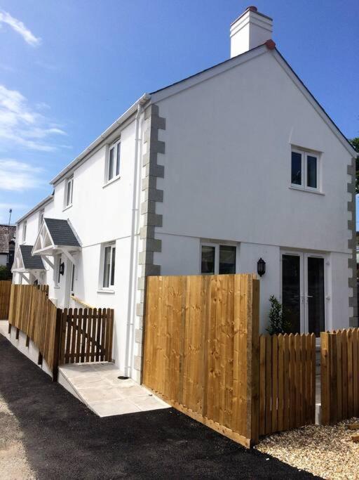 a white house with a wooden fence in front of it at Chy Bownder Cottage in Lostwithiel