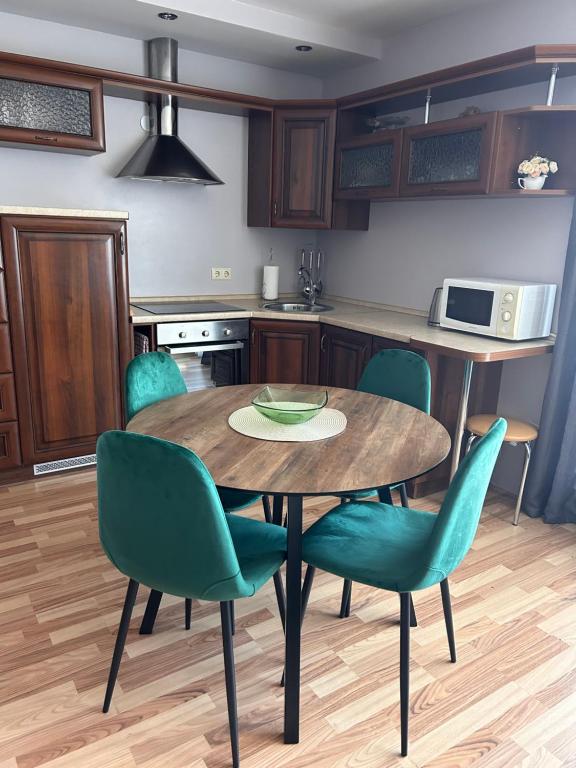 une cuisine avec une table en bois et des chaises vertes dans l'établissement Baltijos 12b Apartamentai, à Klaipėda