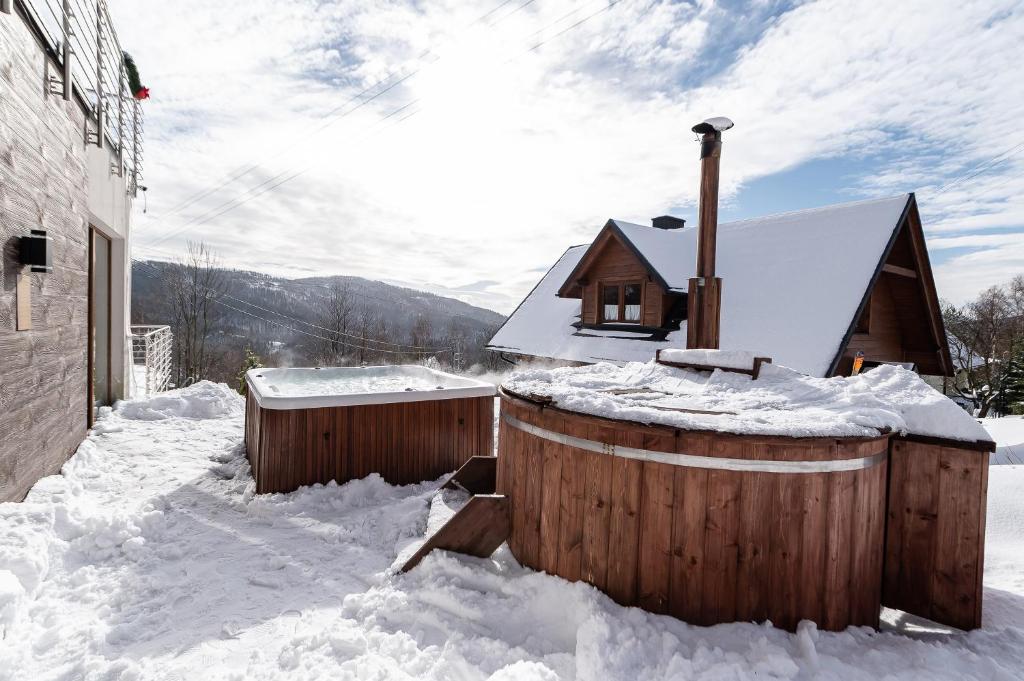 a house covered in snow next to a building at Willa Żar in Bialskie