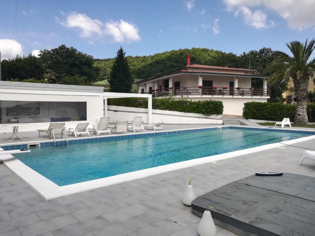 a swimming pool with chairs and a house at Villa Assunta con piscina in Benevento