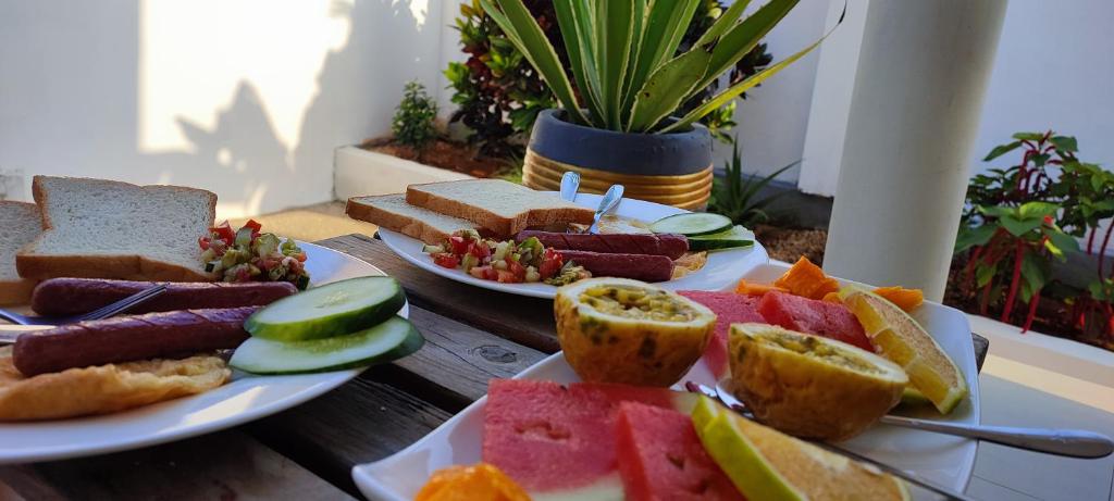 a table with two plates of sandwiches and fruits and vegetables at Garden pearls in Nungwi