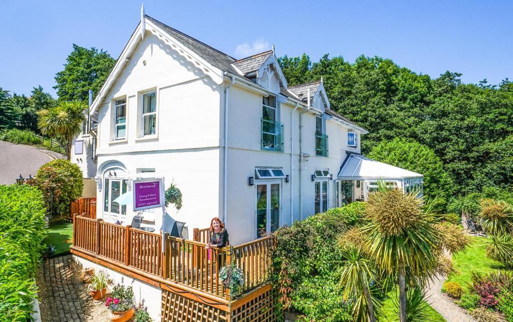 a woman standing on the balcony of a white house at Westwood Guest House - Room Only in Lyme Regis