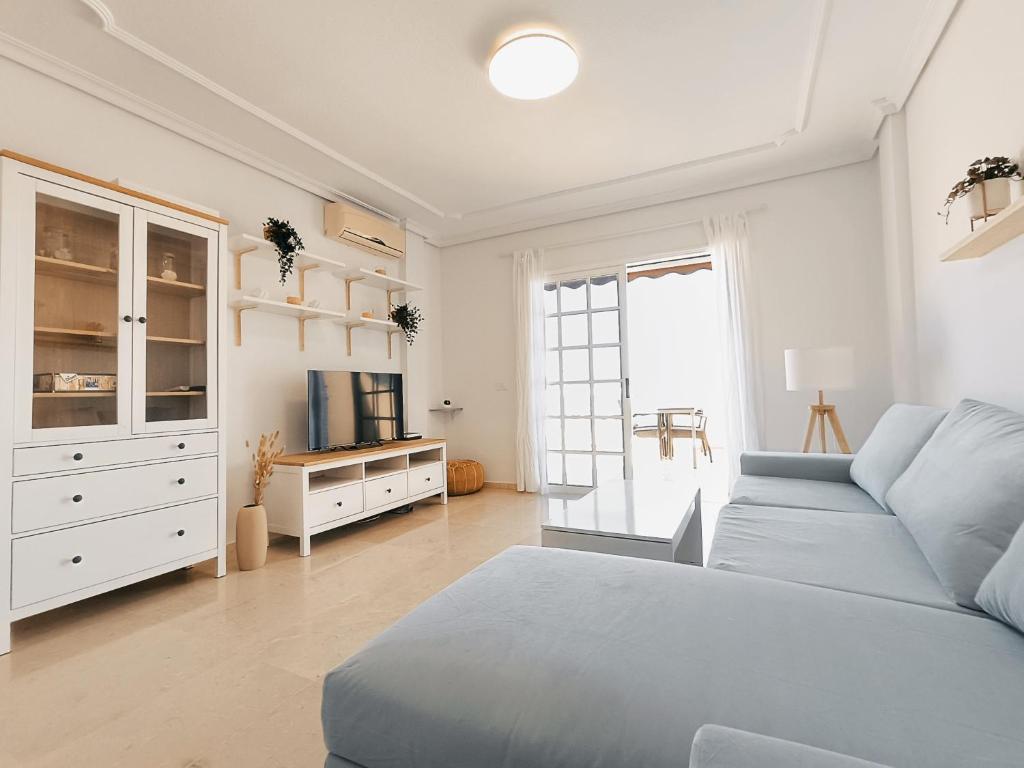 ein weißes Schlafzimmer mit einem blauen Bett und einem Sofa in der Unterkunft Charming & Sunny Apartment with Ocean View in Adeje