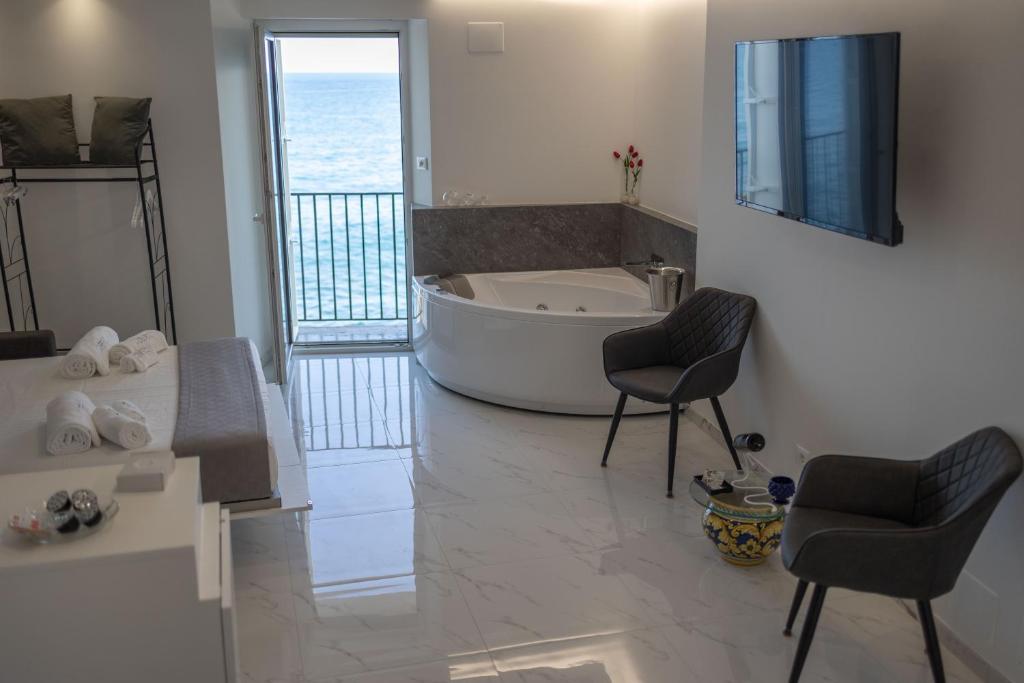 a bathroom with a tub and a table and two chairs at U Scrusciu d’u Mari Luxury Suite in Cefalù