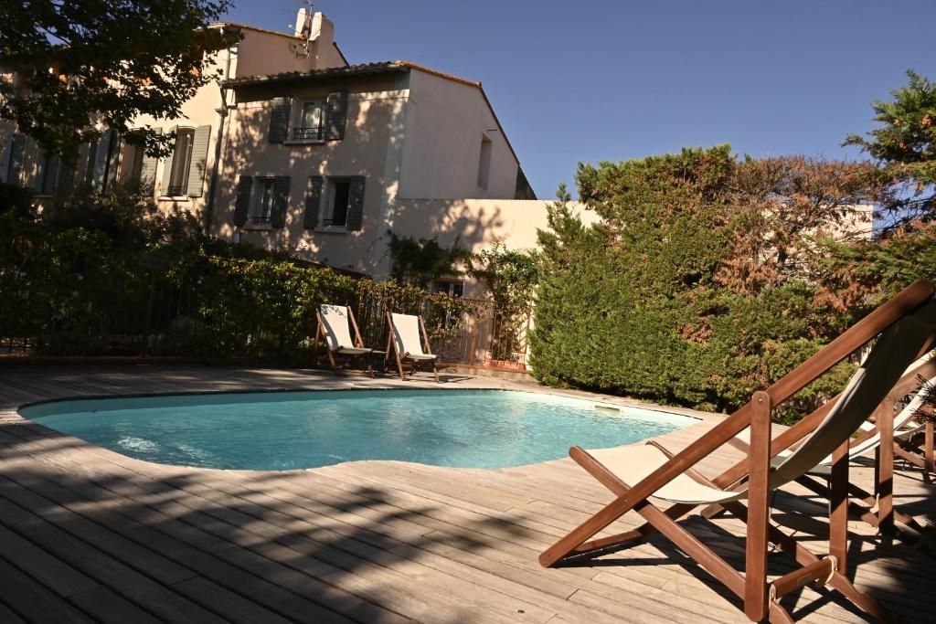 einen Pool mit zwei Stühlen neben einem Haus in der Unterkunft Bastide le Petit Clos - les 2 Gîtes in Perpignan