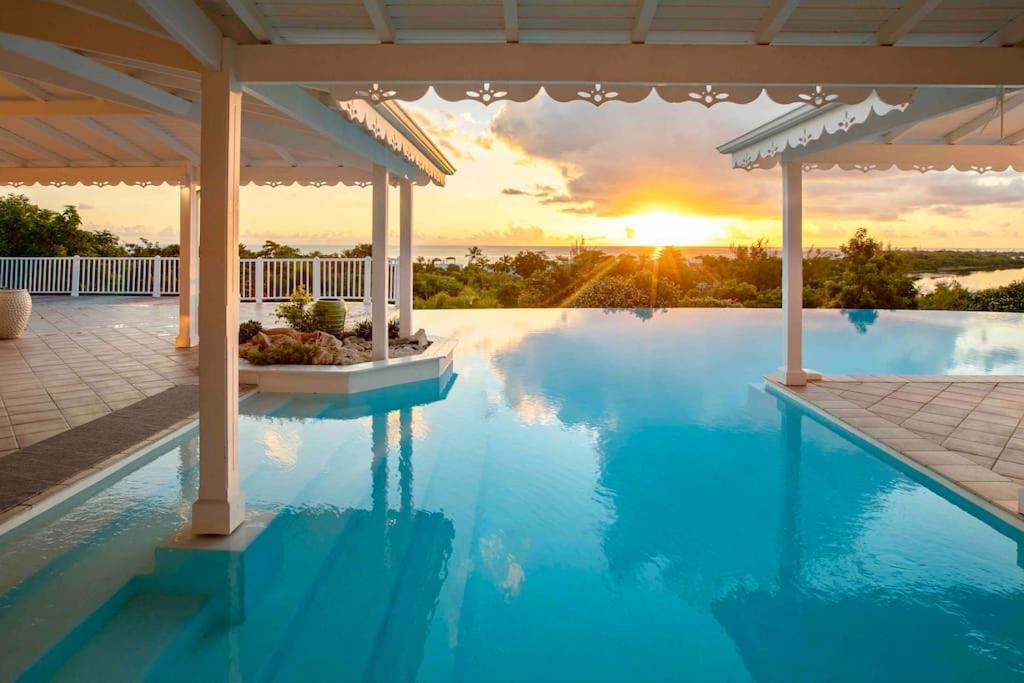 een zwembad met een zonsondergang op de achtergrond bij Villa La Josephine, Terre Basses in Baie Longue