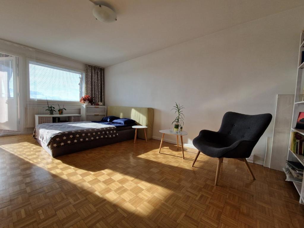 1 dormitorio con 1 cama y 1 silla negra en Big room with balcony in a shared apartment in the center of Kerava, en Kerava