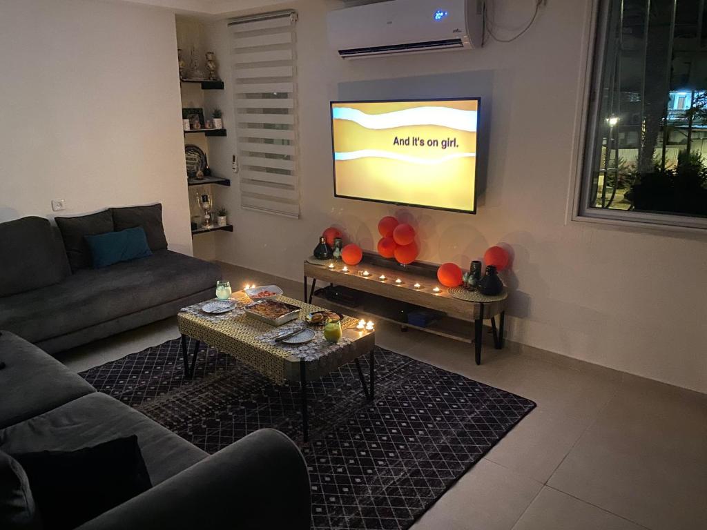 uma sala de estar com um sofá e uma televisão de ecrã plano em ביקתה בים em Tel Aviv