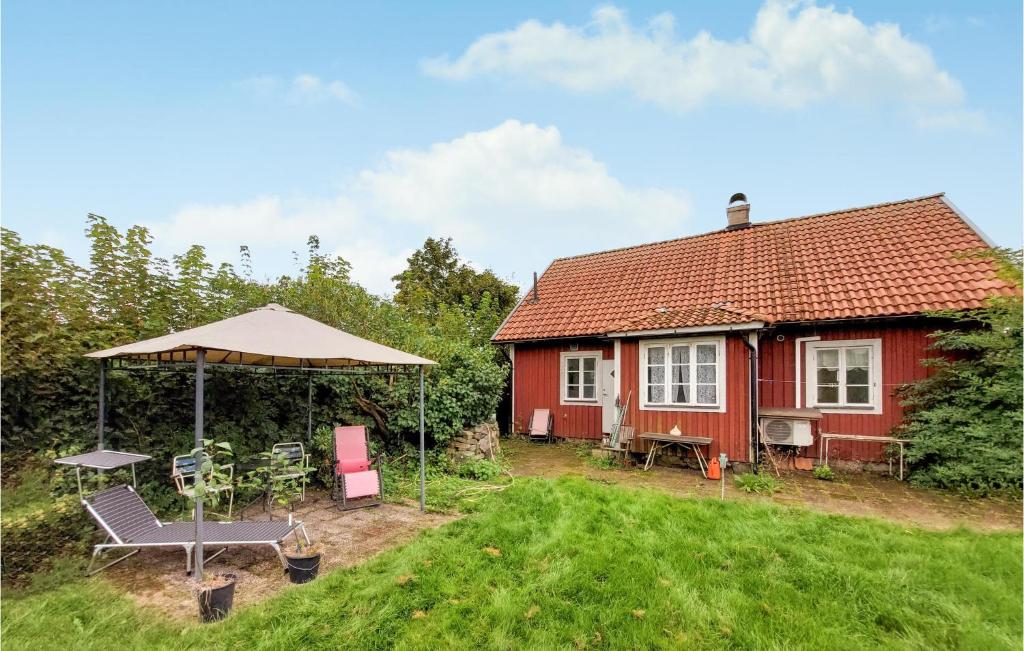 a small red house with a picnic table and an umbrella at Stunning Home In Vinslv With Kitchen in Vinslöv