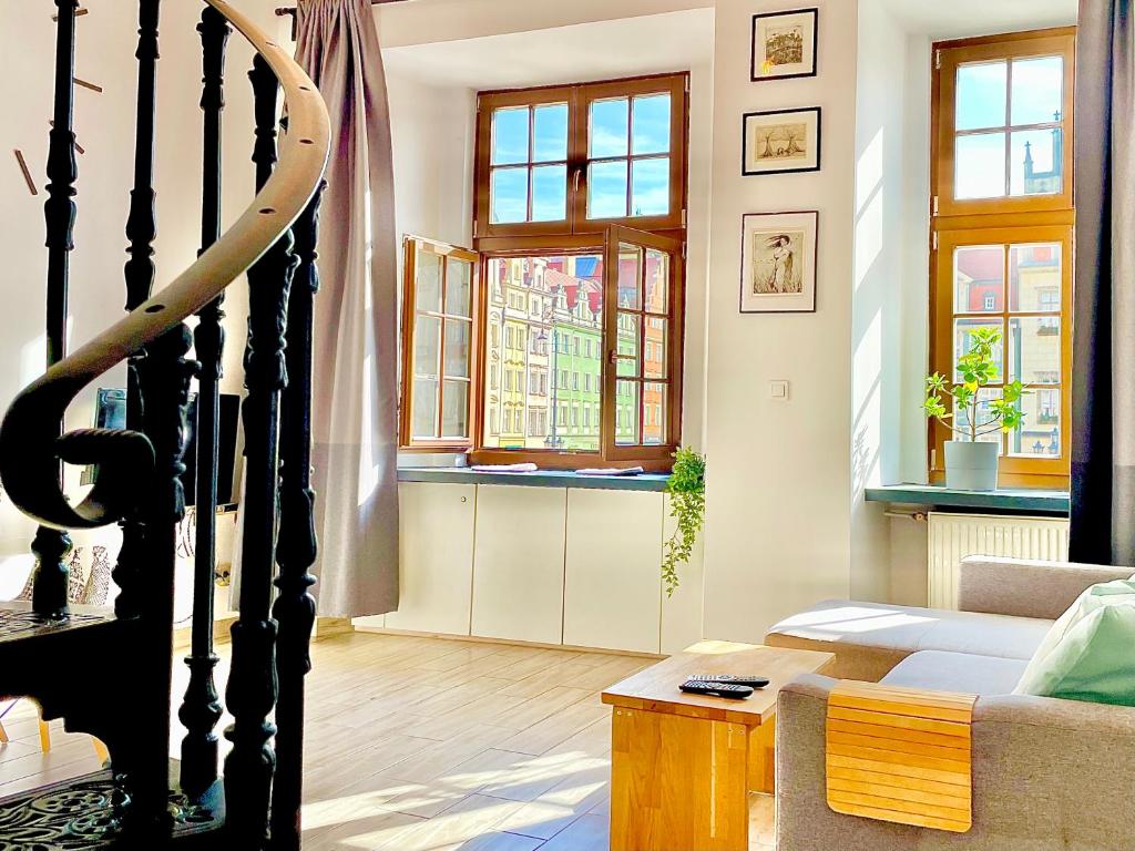 - un salon avec un canapé et des fenêtres dans l'établissement Wroclaw Inn Apartments, à Wrocław