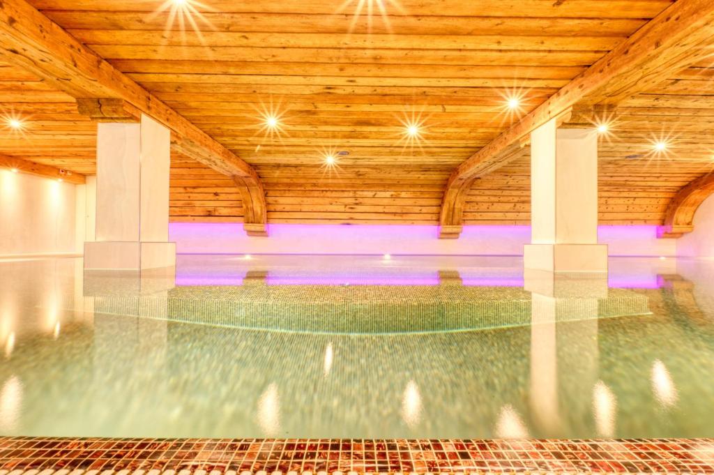 Hotel Arca Solebad & Spa في زيرمات: مسبح داخلي بسقف خشبي