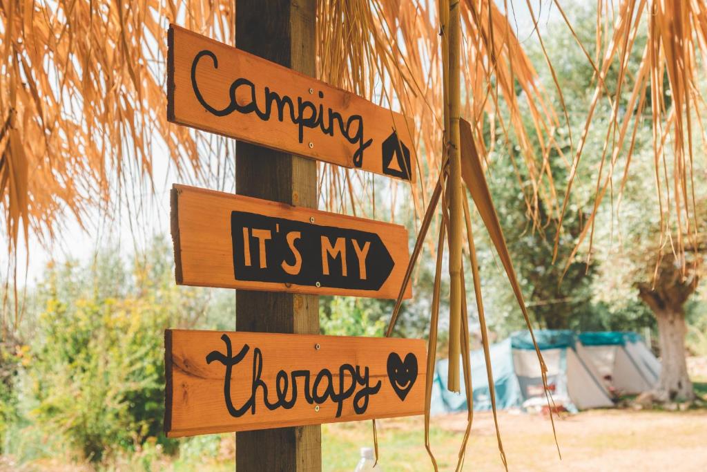 Eine Stange mit Schildern, die sagen, Camping ist meine Therapie. in der Unterkunft Olive Camping in Himarë