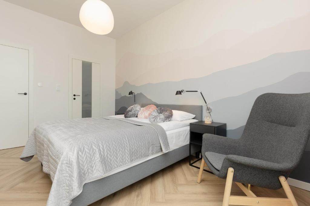 a bedroom with a bed and a chair at Cozy & Spacious Family Apartment by Renters in Warsaw