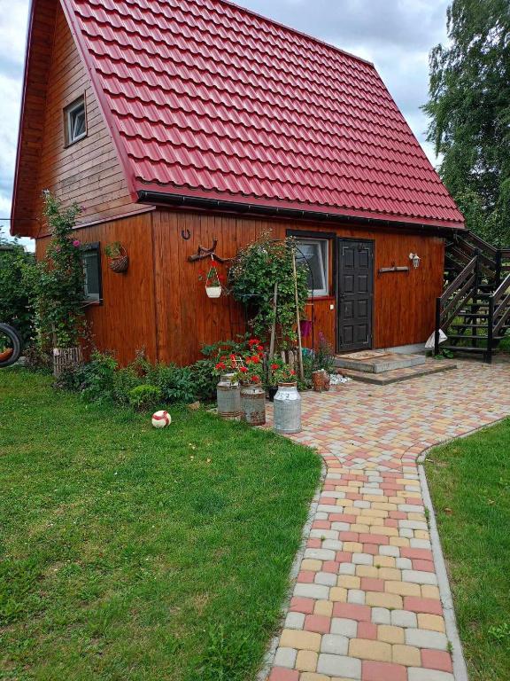 a house with a red roof and a brick path leading to it at DOMEK LETNISKOWY PRZY GÓRACH MAJOWYCH in Goniadz