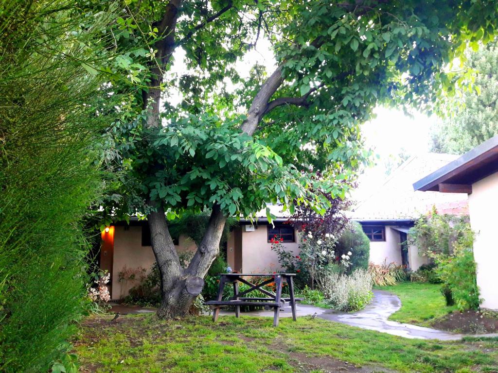 uma mesa de piquenique debaixo de uma árvore ao lado de uma casa em Cabañas Los Nonos em El Bolsón