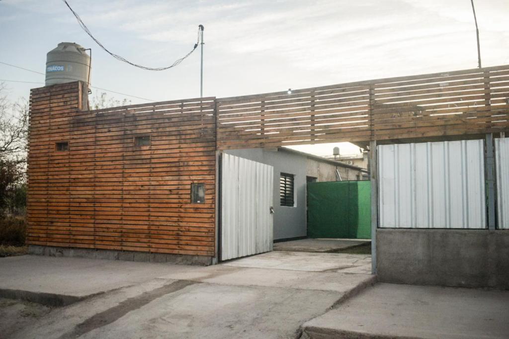 ein Backsteingebäude mit einer weißen Tür und einer grünen Garage in der Unterkunft Fh departamentos in La Rioja