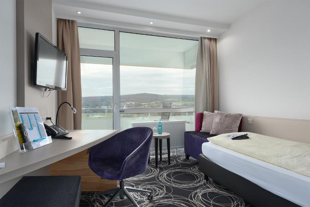 a hotel room with a bed and a desk and a window at Trip Inn Landhotel Badsoden-Salmünster in Bad Soden-Salmünster