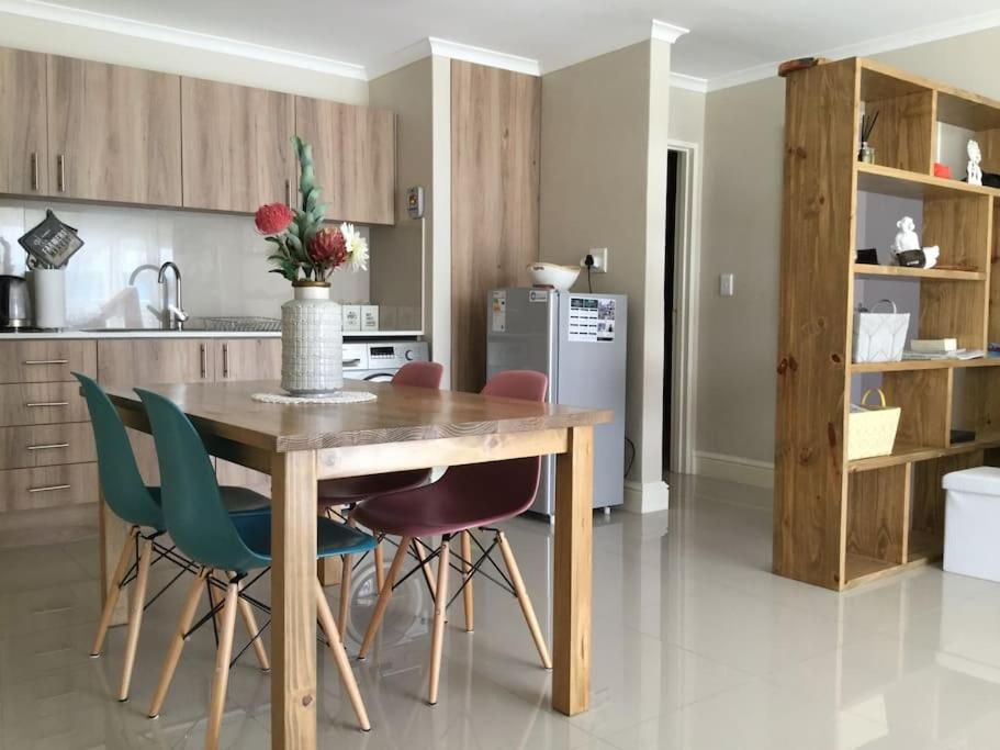 a kitchen with a wooden table and green chairs at Appartamento Azure 23 - Big Bay in Big Bay
