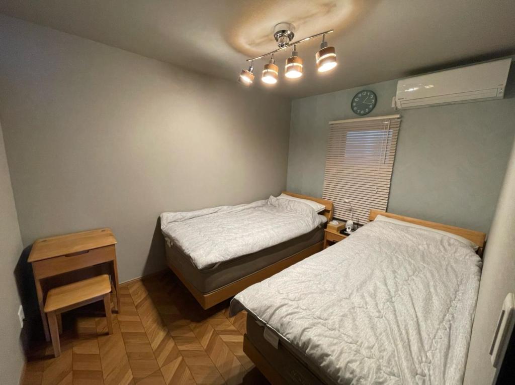 1 dormitorio con 2 camas, mesa y ventana en Guest House Numazu Port - Vacation STAY 18050v en Numazu