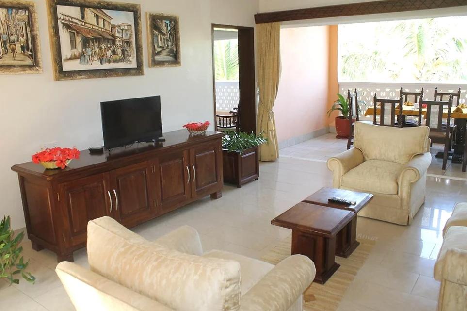 een woonkamer met banken en een flatscreen-tv bij Sun N Sand Beach Resort in Mombasa