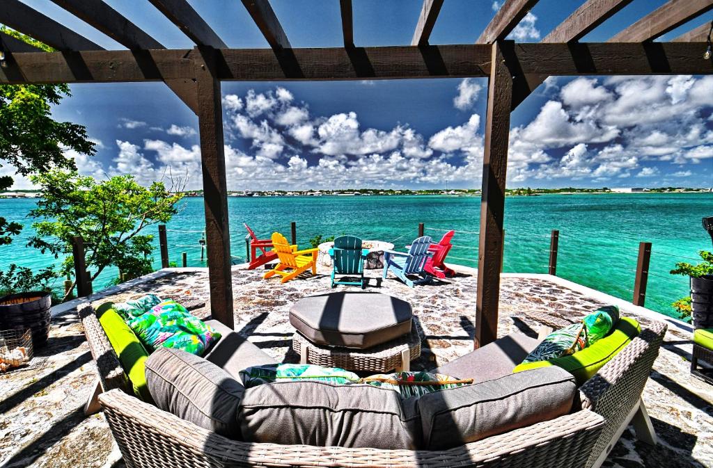 um pátio com um sofá, cadeiras e água em Harbour Beach Villa - large dock & great views! em Marsh Harbour