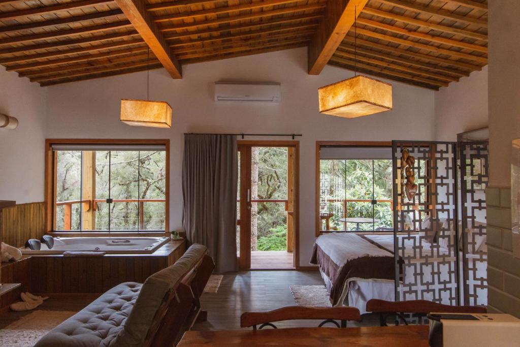 um quarto com uma cama, um sofá e janelas em Pousada Canto da Nascente em Monte Verde