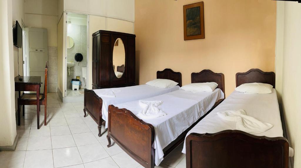 um quarto com 2 camas e lençóis brancos em Hotel América no Recife