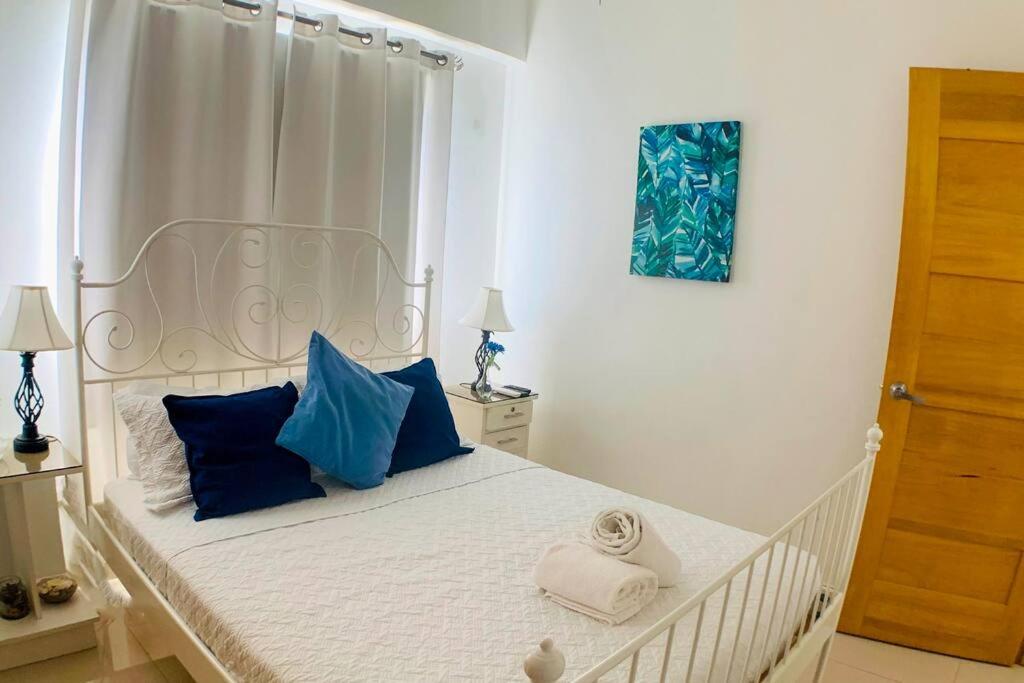 1 dormitorio con cama blanca y almohadas azules en Boca del Mar, Torre II, Apto. 402, en Cuevas