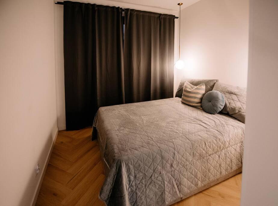 a bedroom with a bed and a window with curtains at obywatelska apartament free parking in Łódź