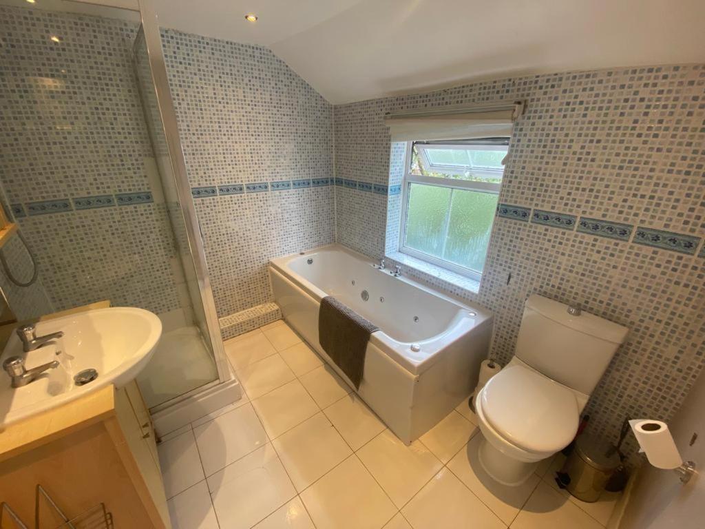La salle de bains est pourvue d'une baignoire, de toilettes et d'un lavabo. dans l'établissement Nice 3 Bedroom House Ealing, à Londres