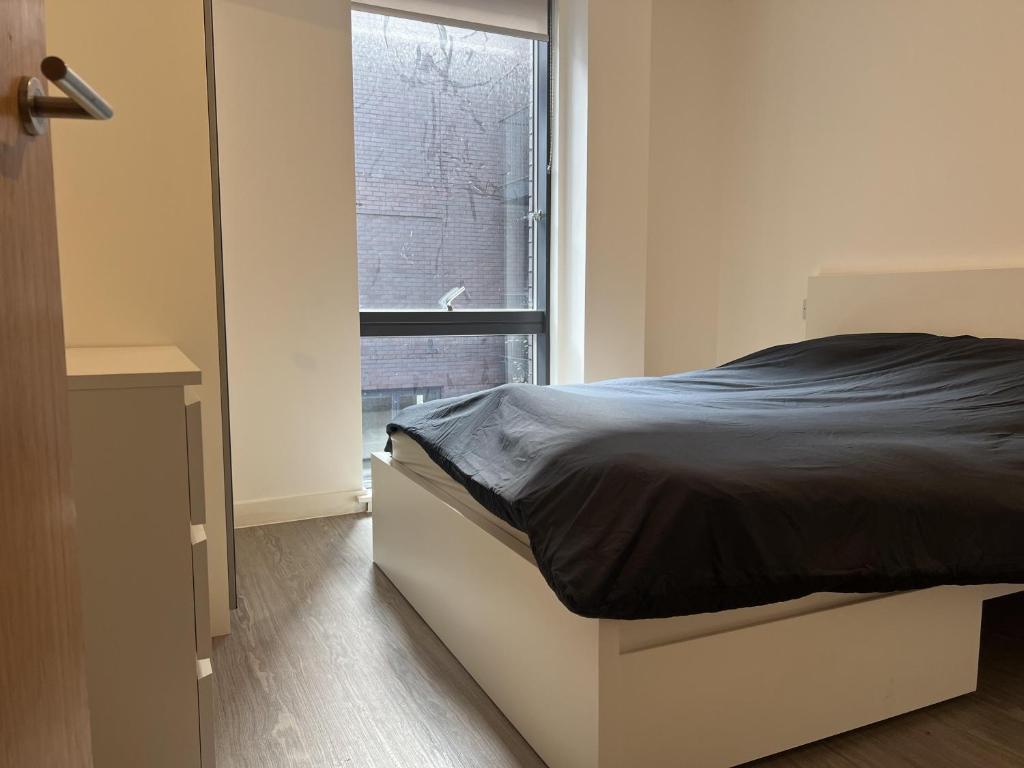 a bedroom with a bed and a window at Charming 2-Bed Apartment in Salford newly built in Manchester