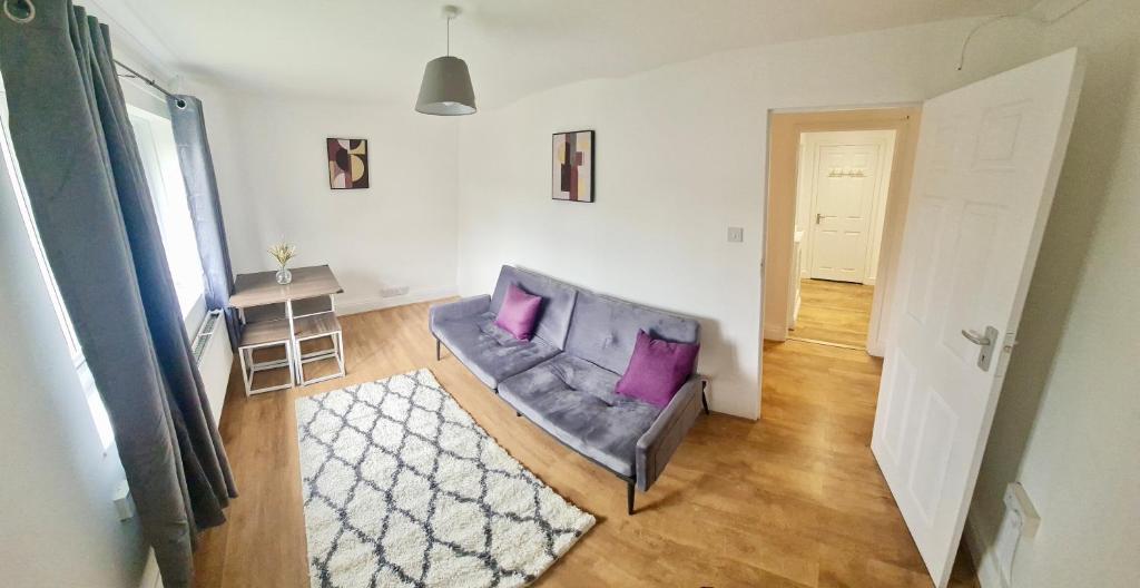 a living room with a couch with two purple pillows at 2 Bed Spacious Apartment, Sleeps 4, Free Wifi, Free Parking, Amenities Nearby, Good Transport Links Nearby, Contractors and Holidays in Harlow