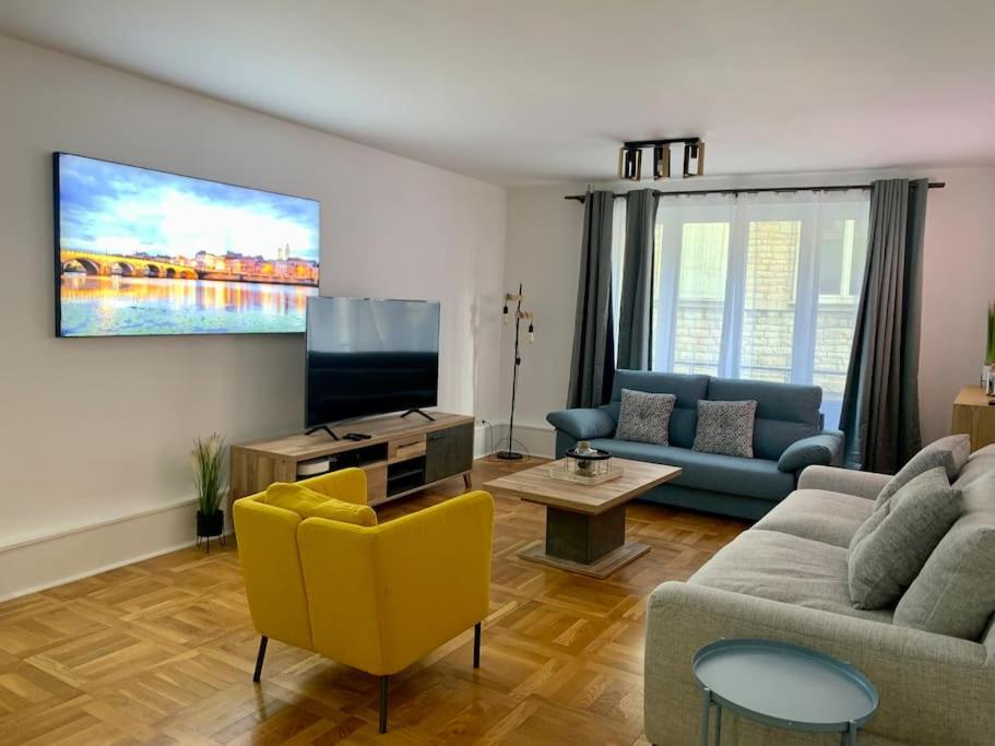 a living room with a couch and a tv at Maison Okaina, Sauna, Au centre-ville de Macon in Mâcon
