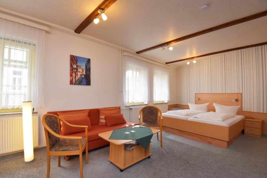 um quarto com uma cama, um sofá e uma mesa em Pension Bergstube em Bad Langensalza
