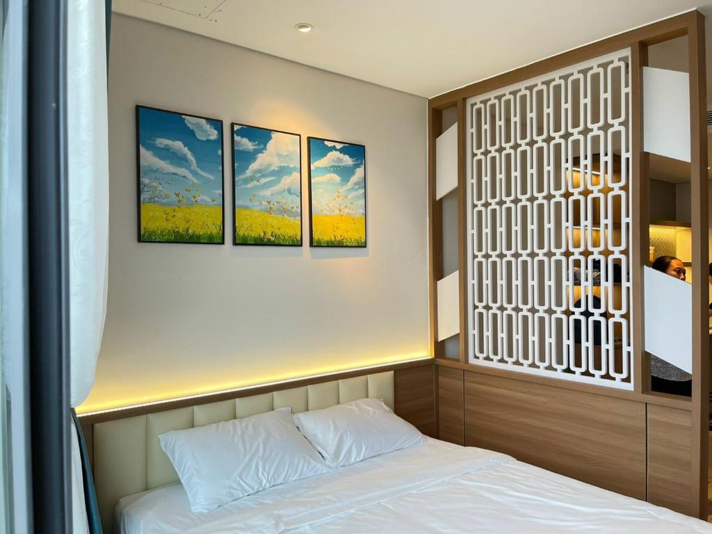 Zimmer mit einem Bett und drei Gemälden an der Wand in der Unterkunft Toàn Tâm Apec in Tuy Hoa