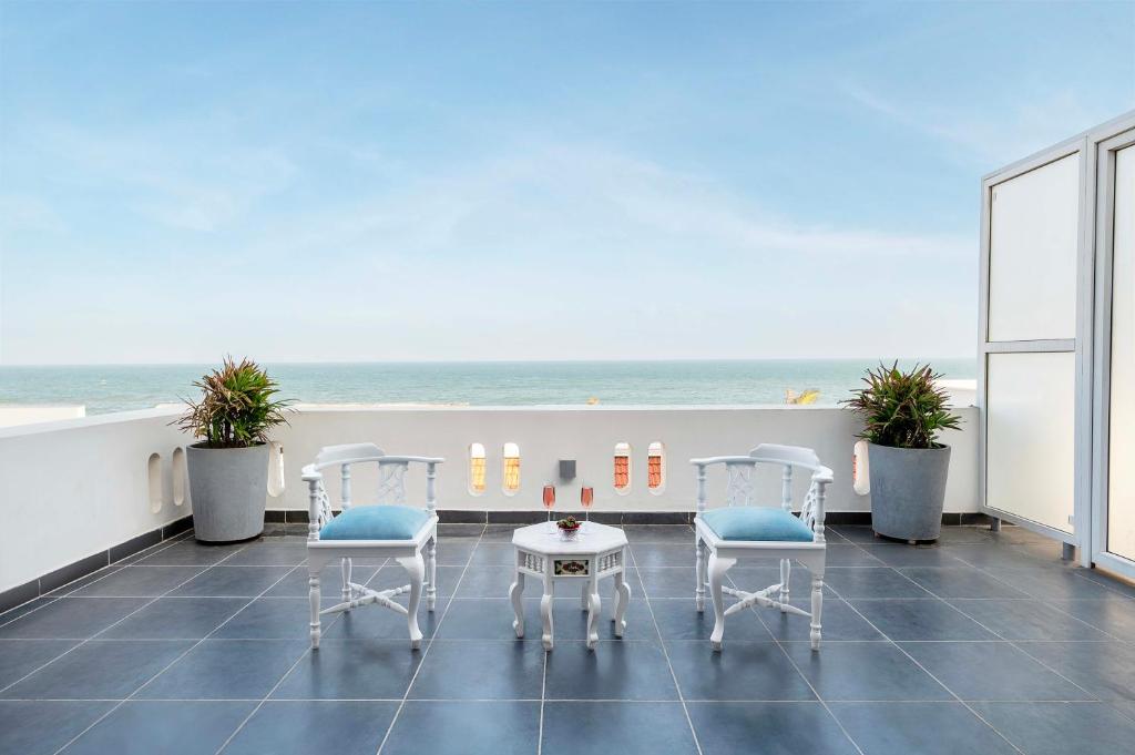 Un balcón con sillas, una mesa y el océano en Villa Cavi en Pondicherry