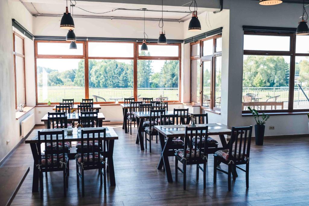 un ristorante con tavoli, sedie e ampie finestre di Penzion Kamence a Liptovský Mikuláš