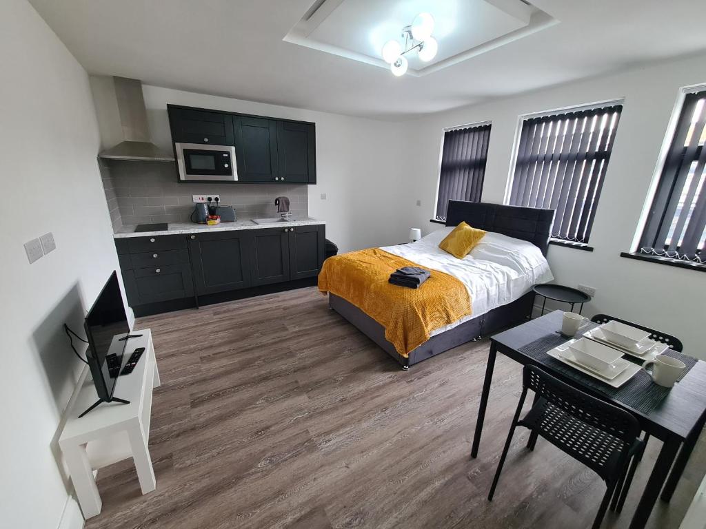 a bedroom with a bed and a table and a kitchen at Homestay by BIC Legends 3 in Batley Carr