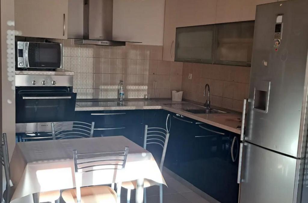 een keuken met blauwe kasten, een tafel en een koelkast bij Harbat in Rustavi