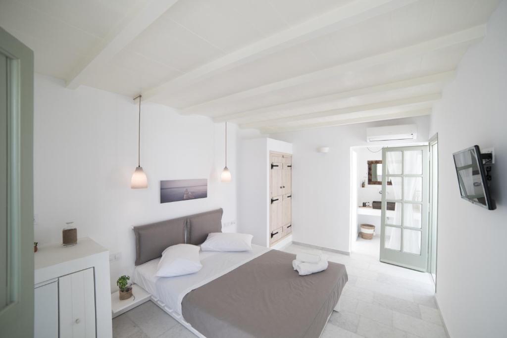 a white bedroom with a bed and a tv at Nastasia Village in Naxos Chora
