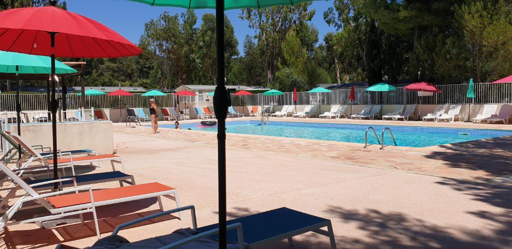 Camping Parc Valrose في لا لوند-ليه-مور: مسبح مع كراسي ومظلات ومسبح