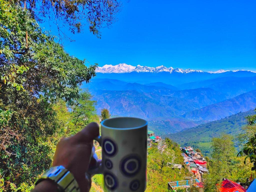 a person holding up a coffee cup in the mountains at Mountain Hideaway in Darjeeling