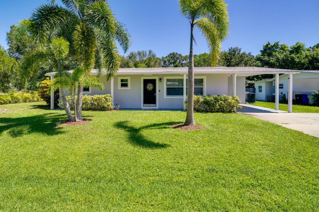 a house with two palm trees in a yard at Dog-Friendly Vero Beach Retreat with Porch and Grill! in Vero Beach