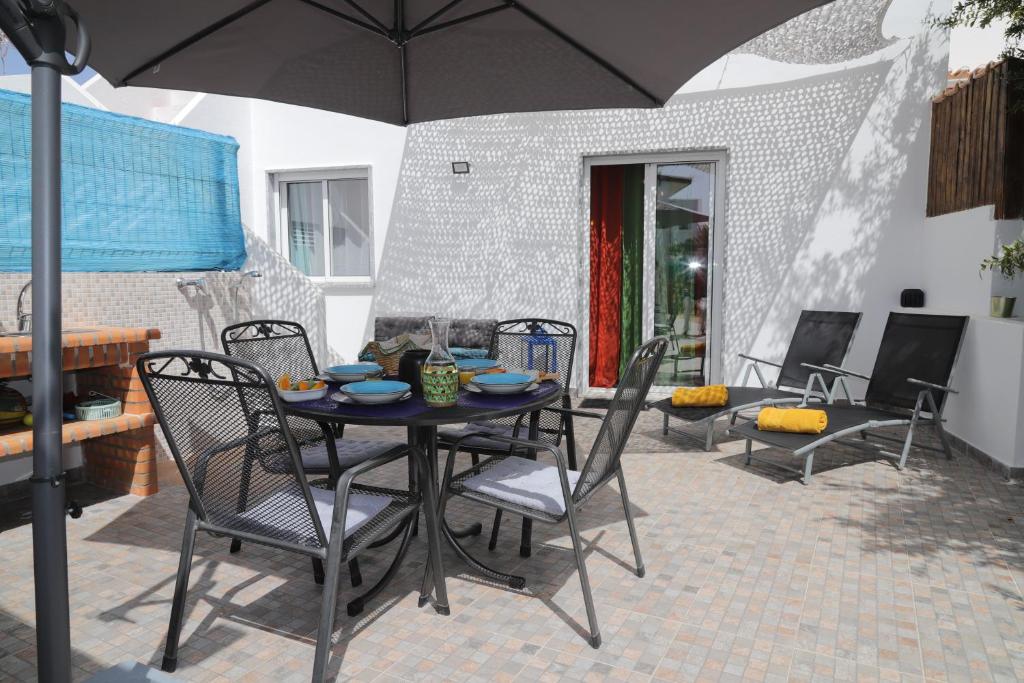 stół i krzesła z parasolem na patio w obiekcie Catita Home w mieście Vila Nova De Cacela