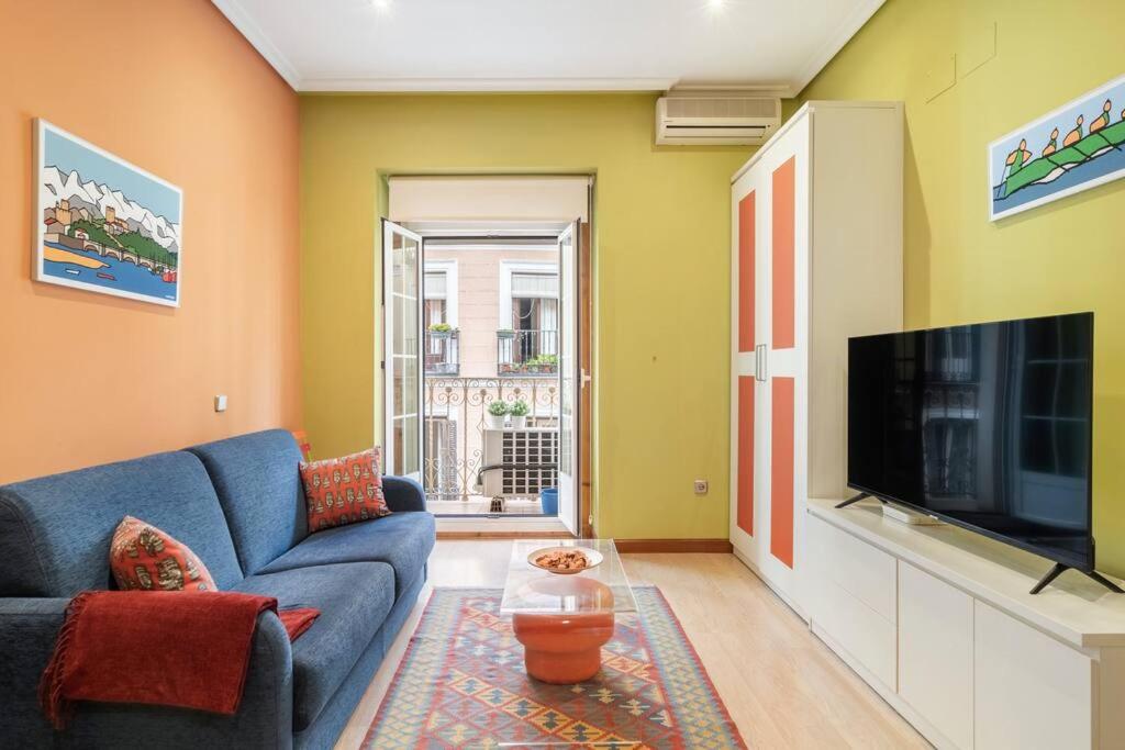 uma sala de estar com um sofá azul e uma televisão em Victor Apartments Chueca II em Madri