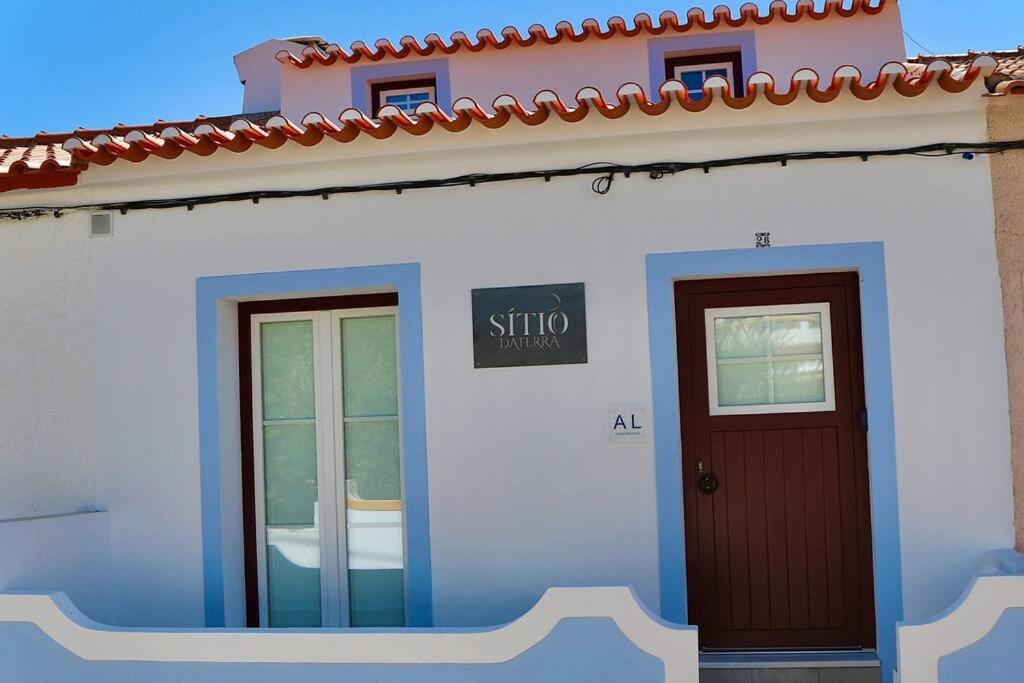 ein weißes Haus mit Tür und Schild drauf in der Unterkunft Sítio DaTerra in Santo António da Terrugem